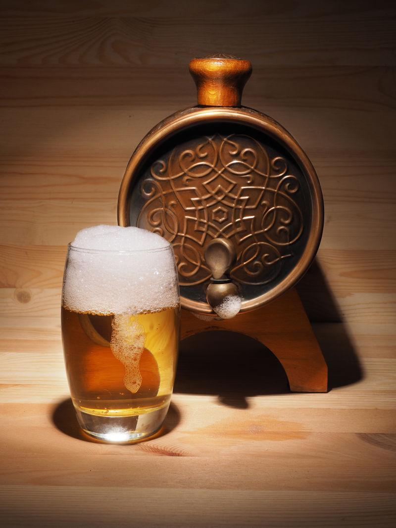 木板上的啤酒桶和一杯冒泡啤酒