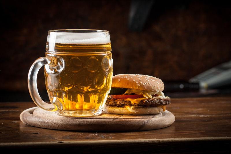 木桌上木盘里的啤酒和汉堡