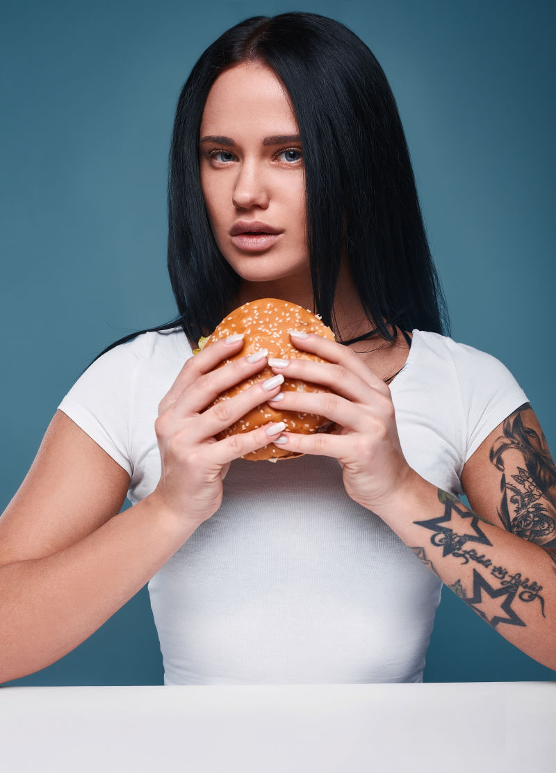 美丽的纹身女孩拿着汉堡包