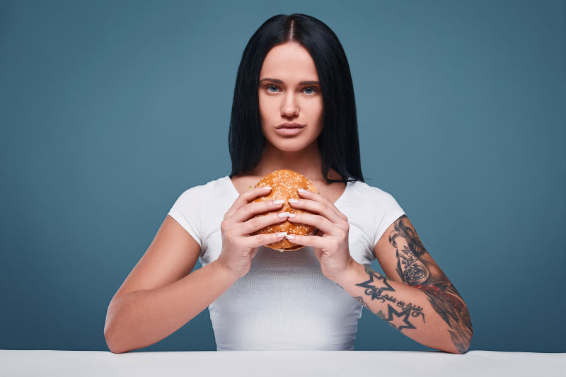 迷人的纹身女孩拿着汉堡包