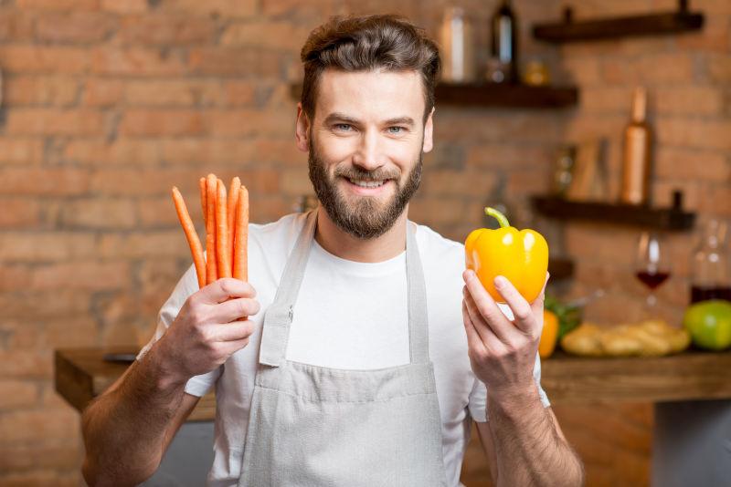 一个健康的男人在厨房里放着黄胡椒和胡萝卜的肖像
