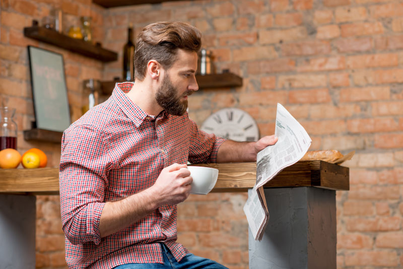 坐在厨房边喝咖啡杯看报纸的帅哥
