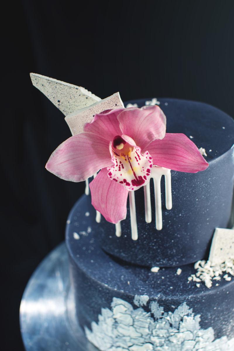 黑色背景下的白色巧克力和兰花装饰婚礼蛋糕