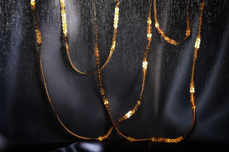 黑色丝绸背景下的金色闪光亮片装饰