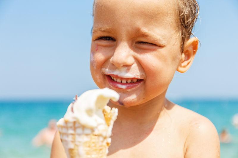 金发男孩正在海滩上开心的吃冰淇淋
