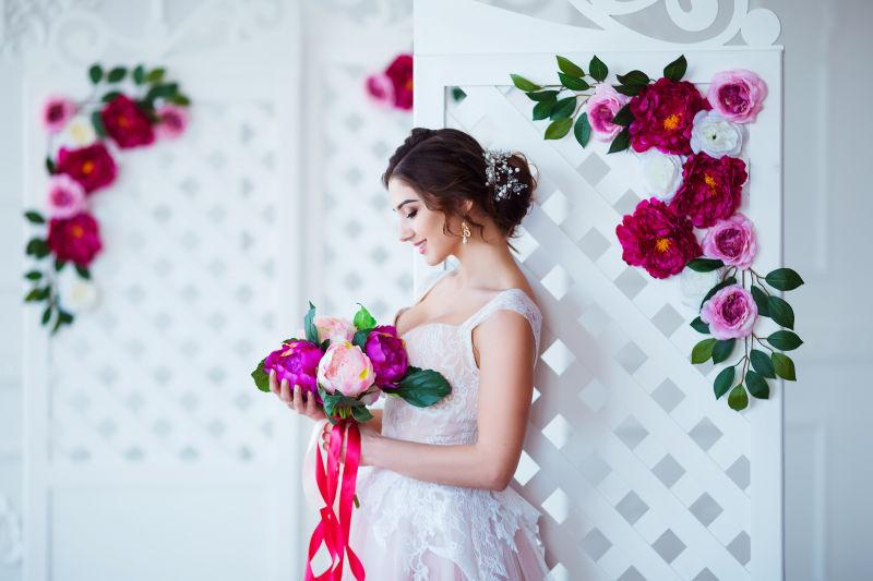 靠在墙上的新娘拿着美丽的花束