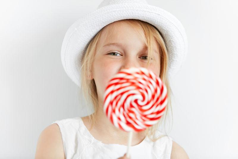 面带笑容的小女孩拿着一块棒棒糖
