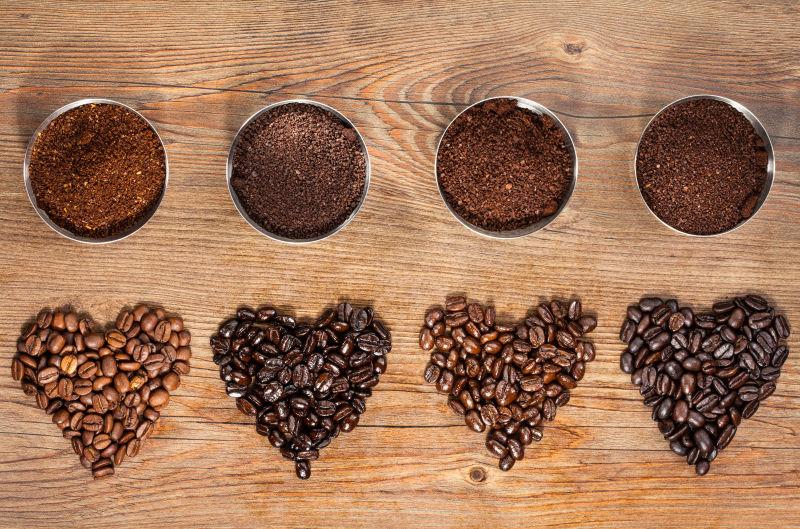 木纹理桌上摆放的不同品种的咖啡豆磨成的咖啡粉