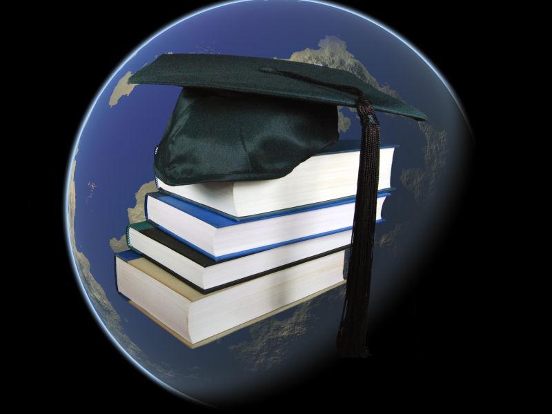 地球背景中的书和毕业礼帽
