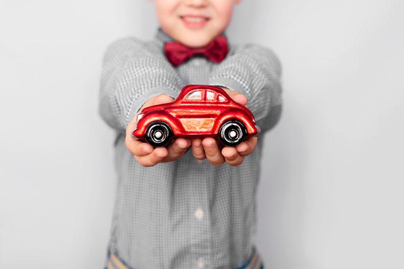 拿着红色汽车模型的小男孩