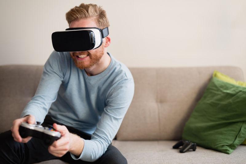 坐在沙发上带着VR眼镜玩游戏的男人