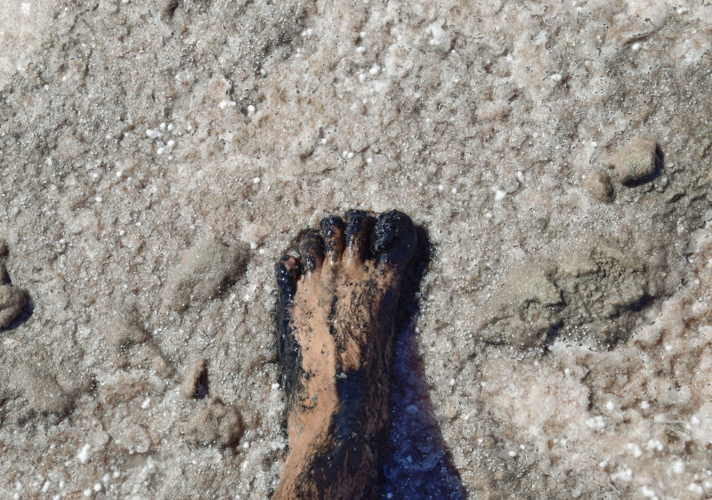 人脚踩在淤泥和盐湖卤水中