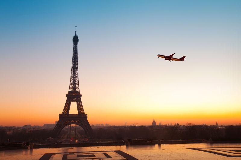 夕阳下空中的飞机飞过巴黎埃菲尔铁塔