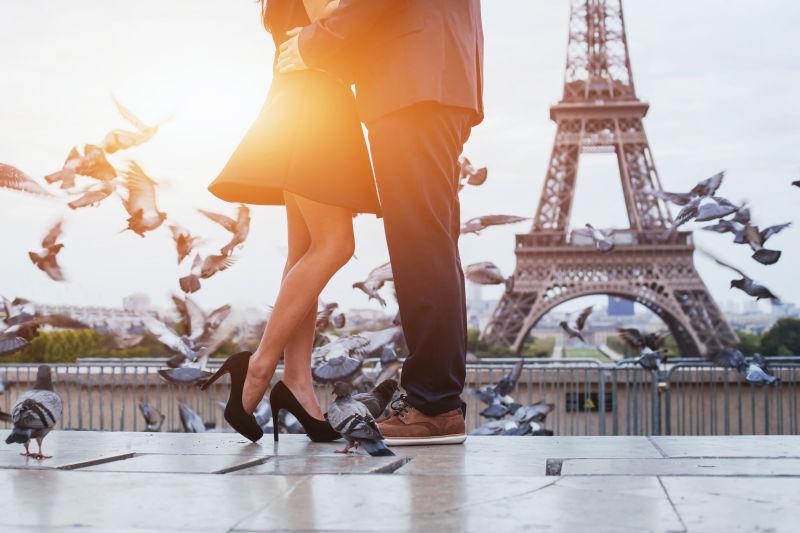 阳光下巴黎埃菲尔铁塔下广场上的鸽子和情侣