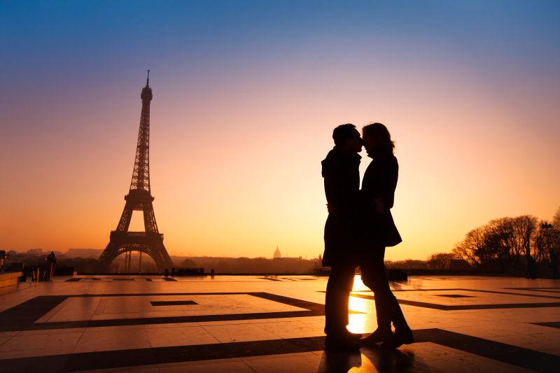 夕阳下的埃菲尔铁塔背景下的接吻的情侣