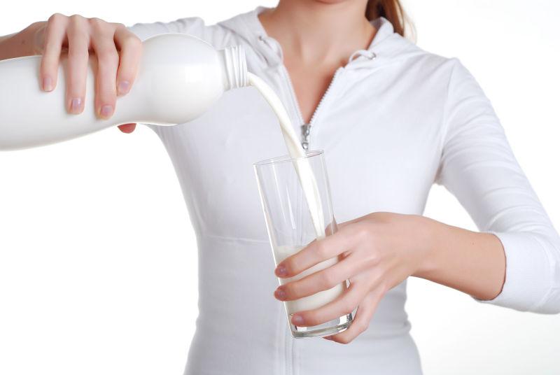 白色背景下拿着玻璃瓶装牛奶的女人