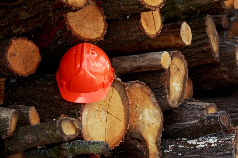 堆砌木材上的橙色防护头盔