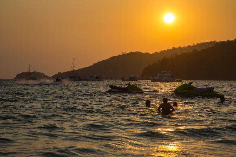 日落时人们在海上玩喷气式雪橇和游艇