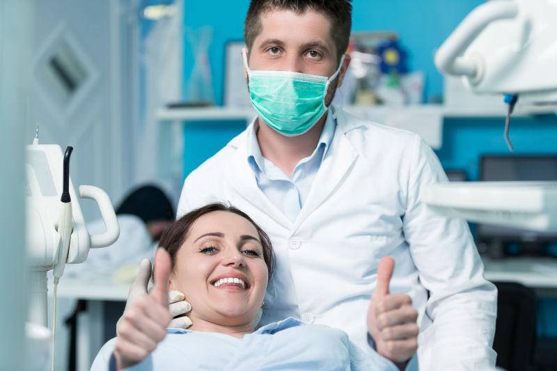 戴口罩的牙医和点赞微笑的病人