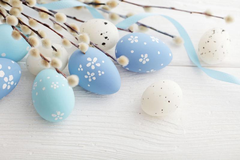 白色木纹理桌上的蓝色复活节彩蛋和白色蛋