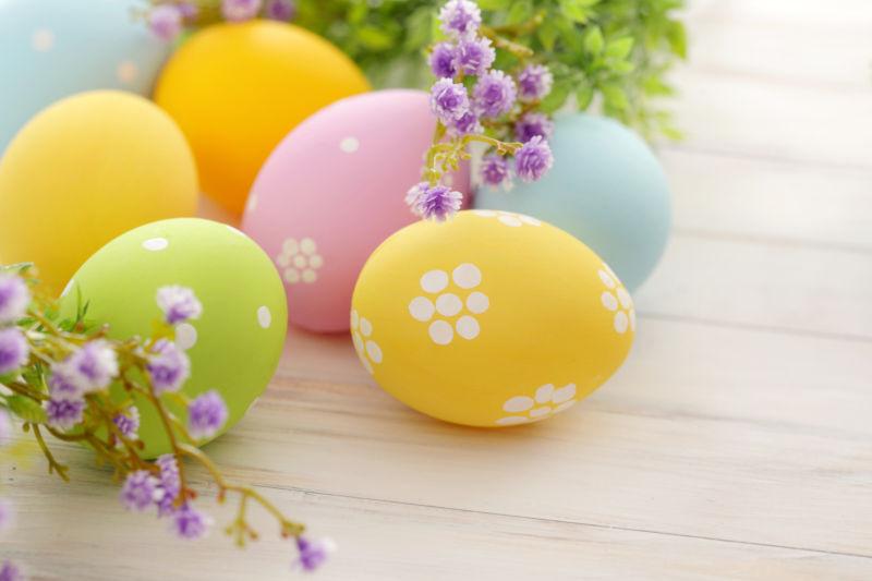 白色木纹理桌上的复活节彩蛋和紫色小花