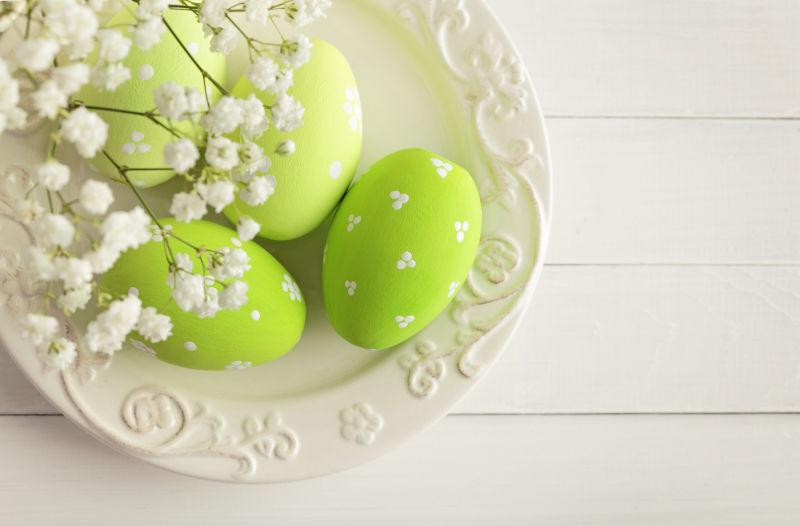 白色桌上白色盘子里的复活节彩蛋和白色满天星花朵
