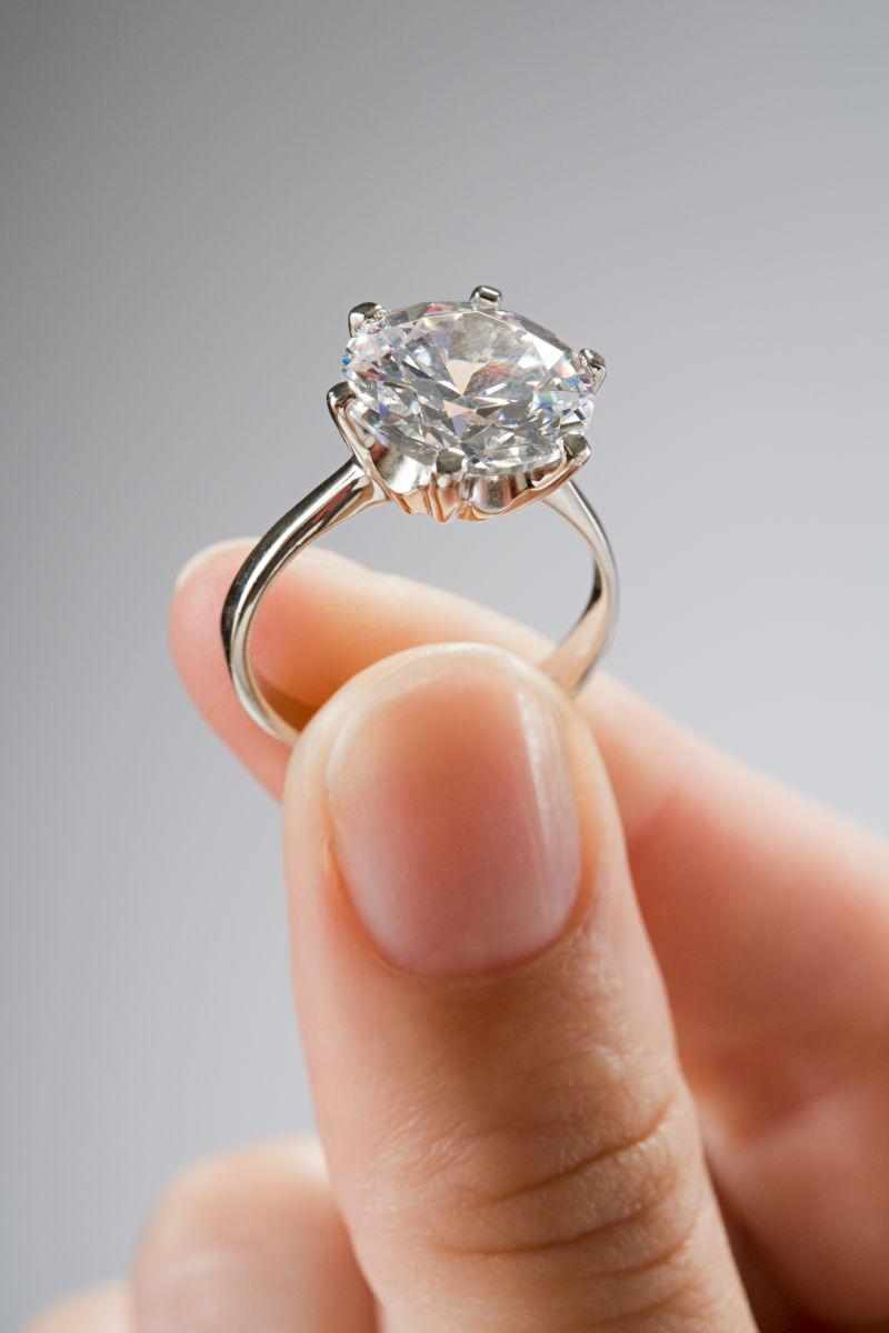 女人拿着一枚钻石戒指