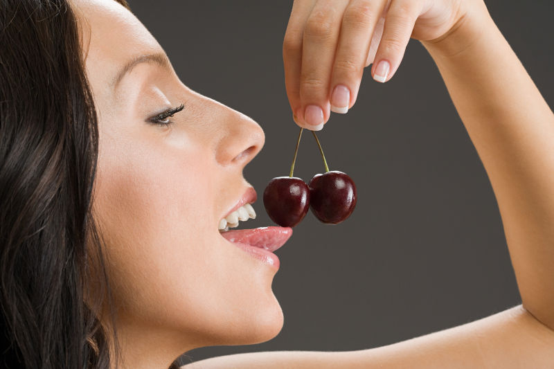 用舌头舔樱桃的女人