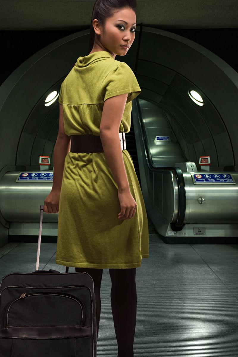 年轻女人提着行李箱走在地铁站里