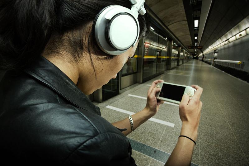 在地铁玩游戏机戴耳机的男人