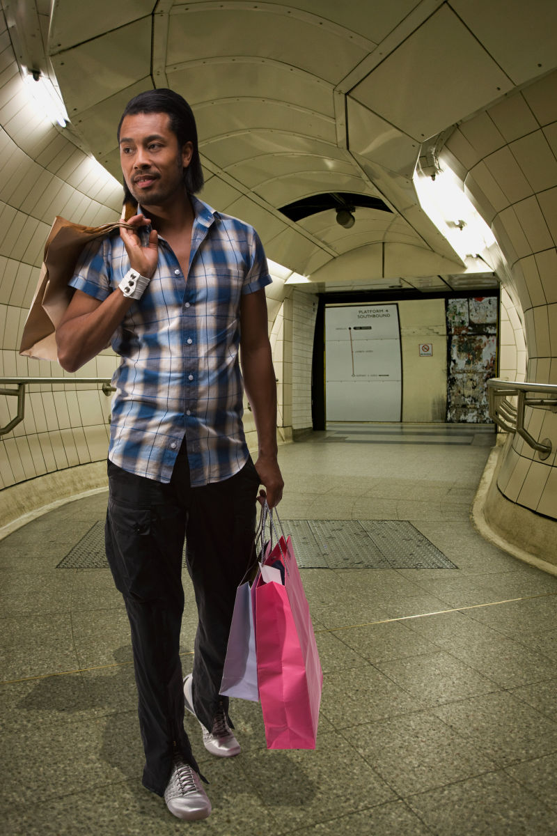 提着购物袋走在地铁站的男人