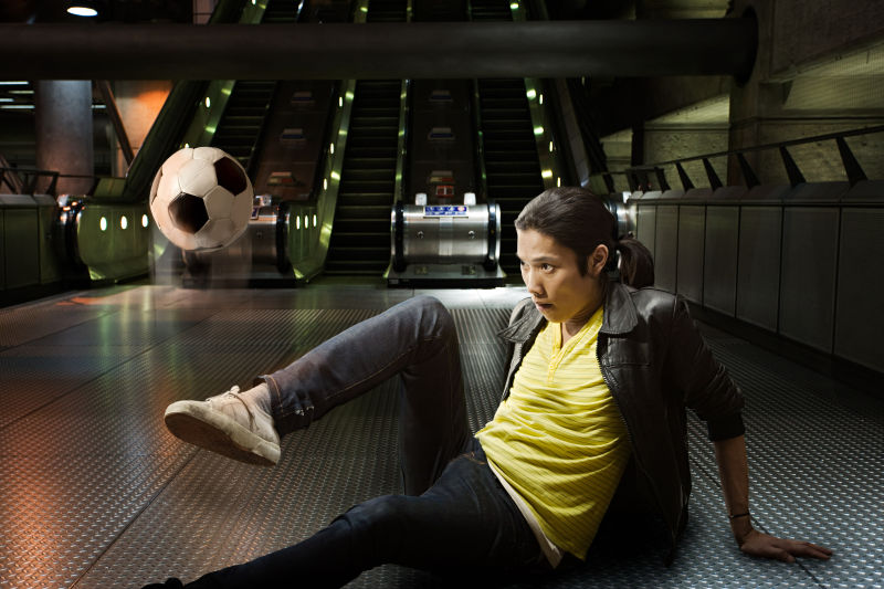 坐在地铁玩足球的男人