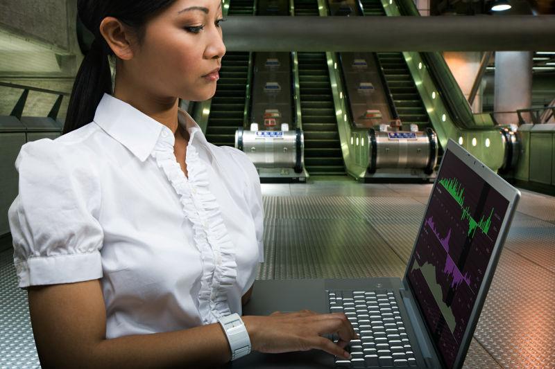 在地铁站使用笔记本电脑的女人