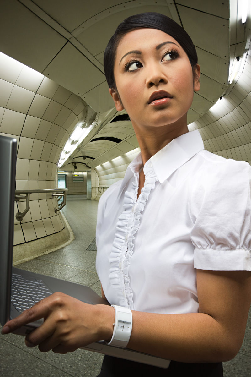 在地铁站里拿着笔记本电脑的女人