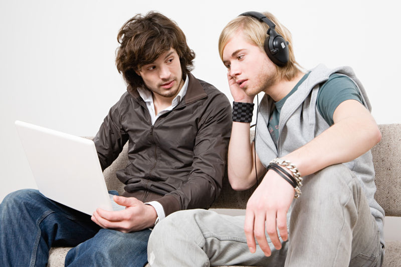 笔记本电脑上听音乐的两个男人