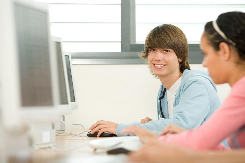 电脑前微笑的男学生