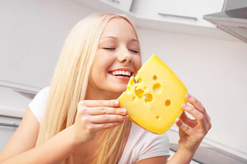在厨房中吃黄色的奶酪的美女