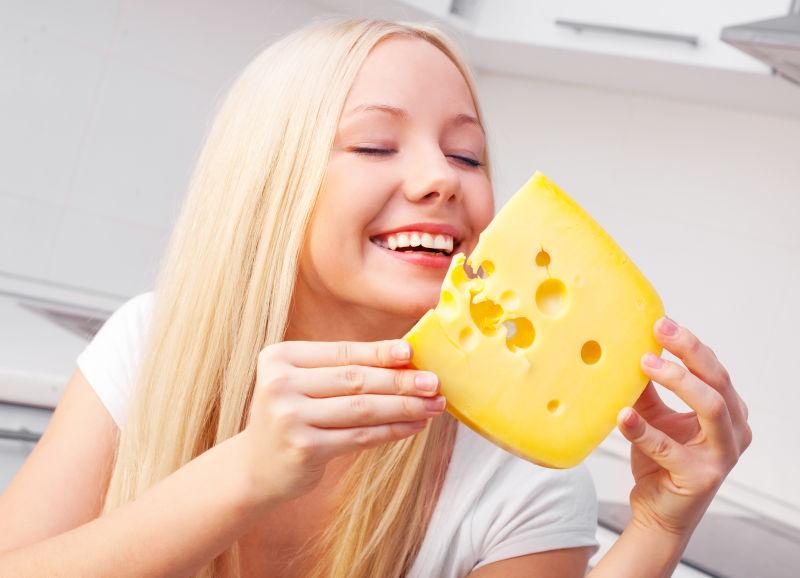 在厨房拿着奶酪微笑的女人