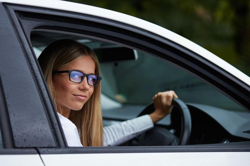 戴眼镜的年轻女子驾驶她的车