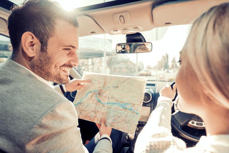 微笑的男人和女人在旅途中使用地图