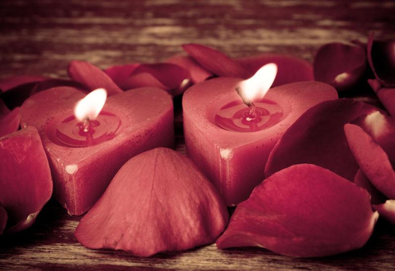 情人节蜡烛在玫瑰花瓣的背景下
