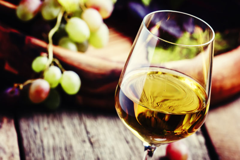 木桌上的葡萄和一杯白葡萄酒