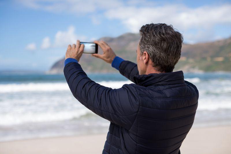 成熟男人用手机拍摄大海