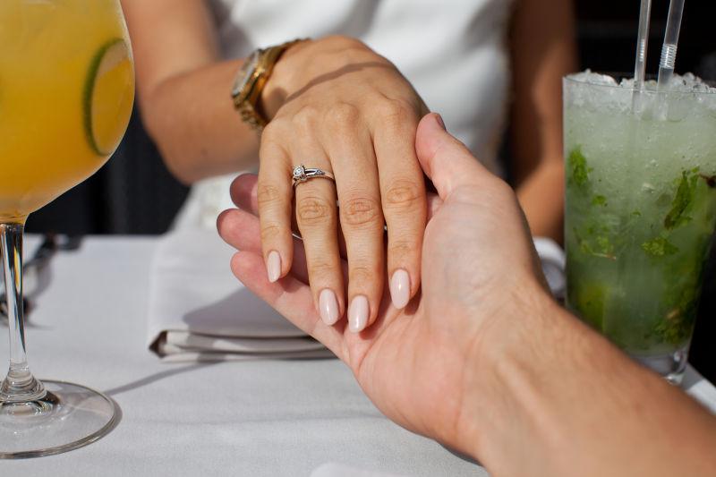 餐厅里男人拖着女友戴着戒指的手