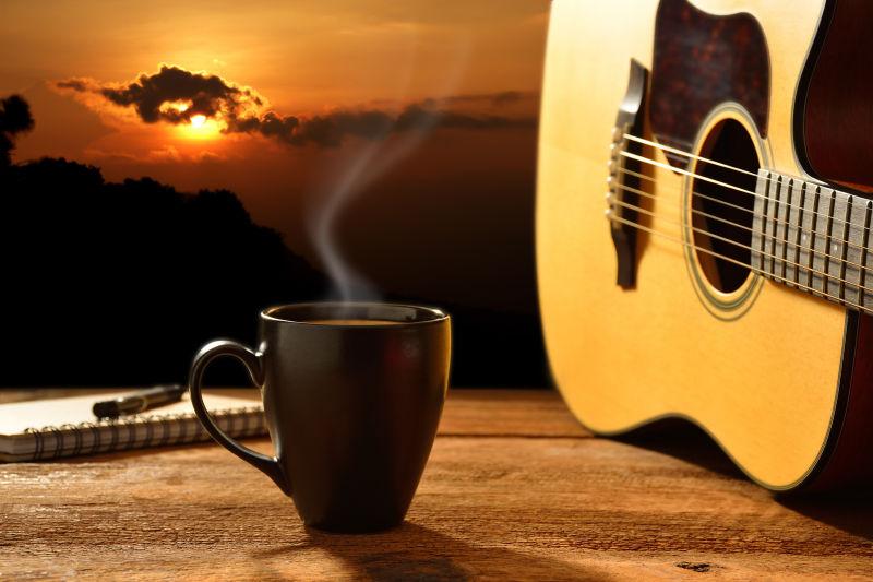 日出-夕阳下的背景下的木桌上吉他旁边的一杯热咖啡