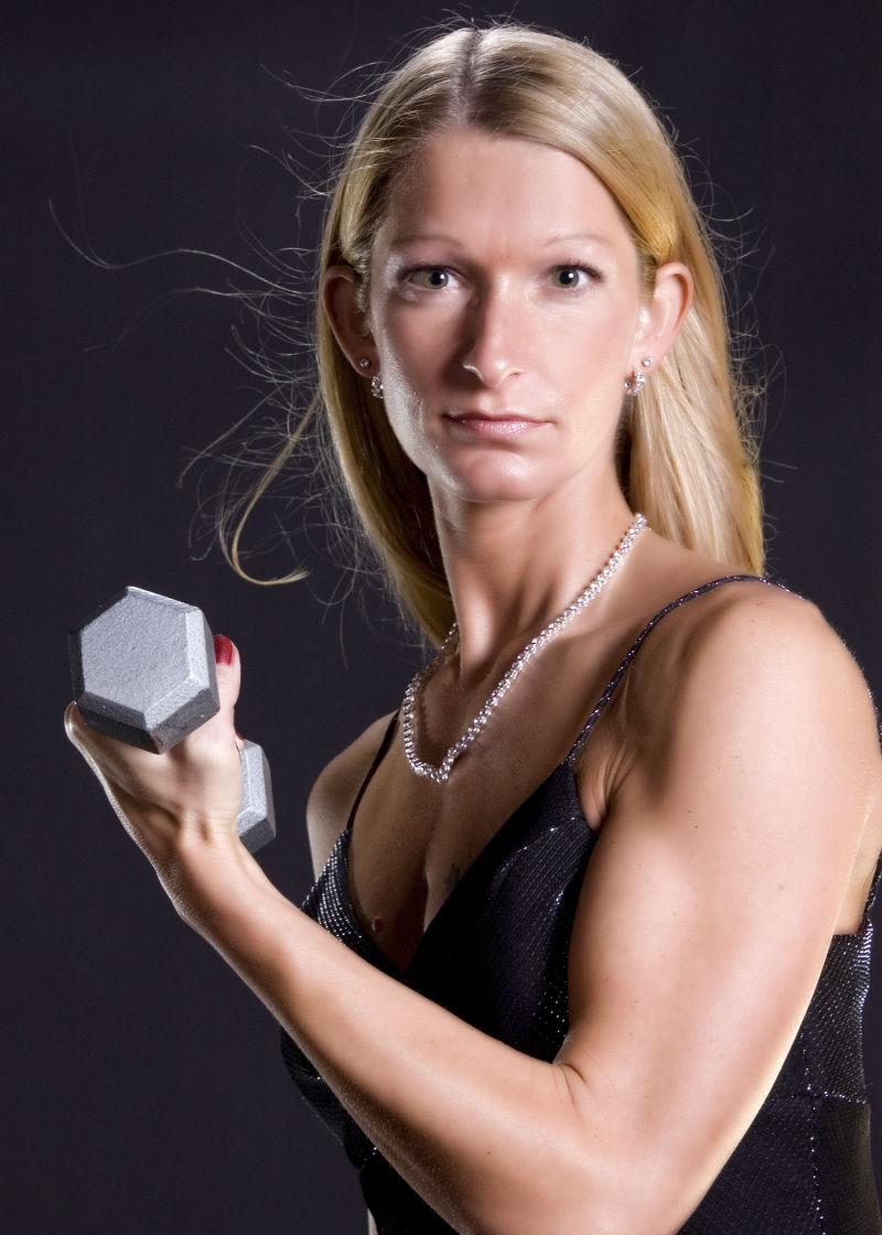 黑色背景下拿着哑铃锻炼身体的女性