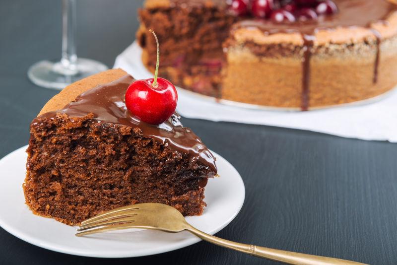 木桌上白色盘里的带有多汁樱桃的巧克力蛋糕
