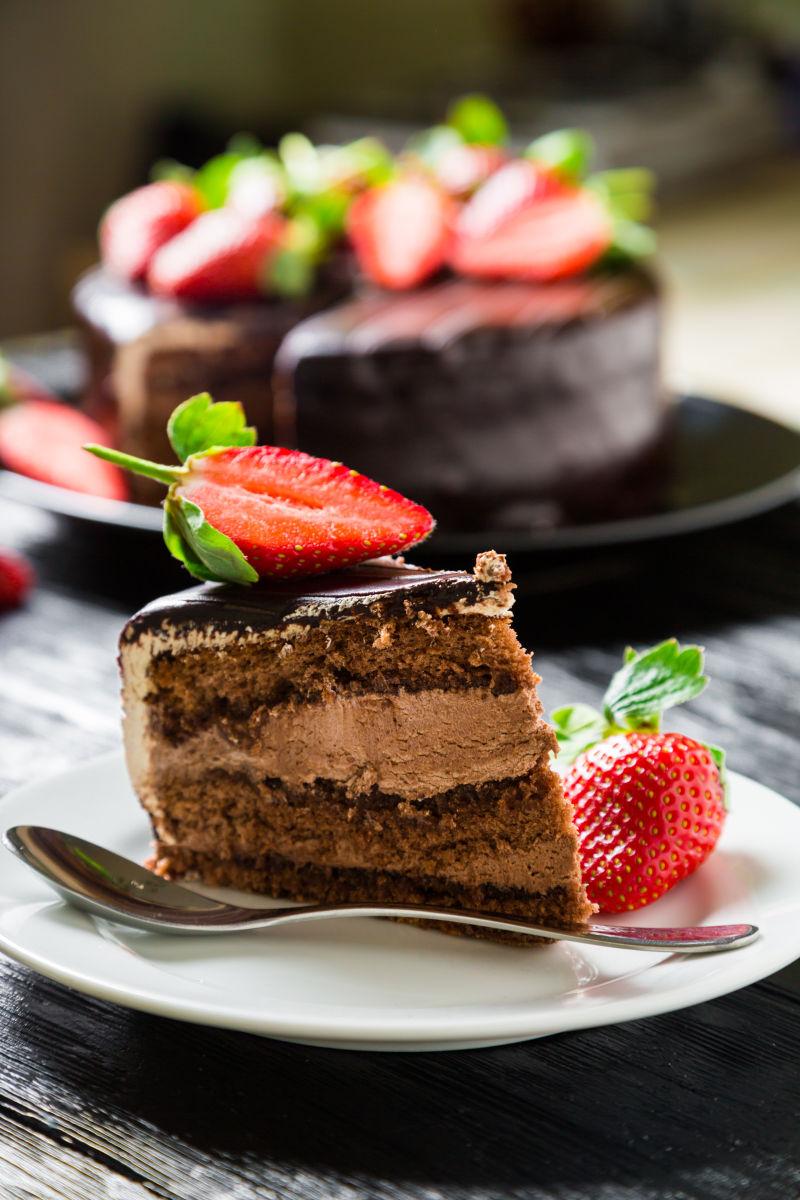 在黑木桌上新鲜草莓巧克力蛋糕