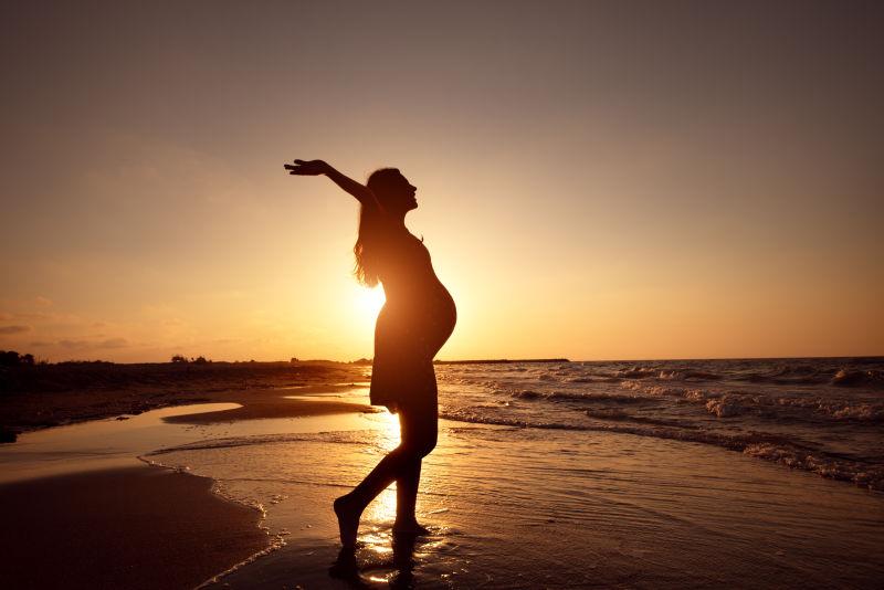 夕阳下海滩上的孕妇