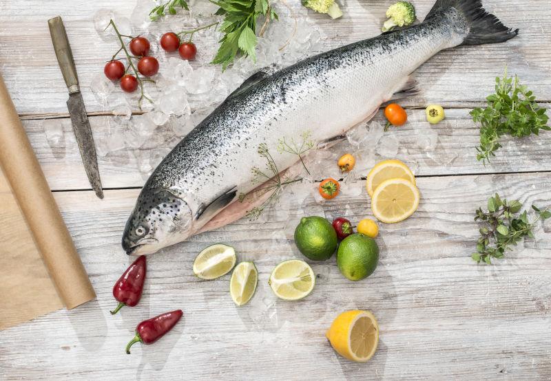 白桌上的新鲜生鱼在冰和蔬菜中